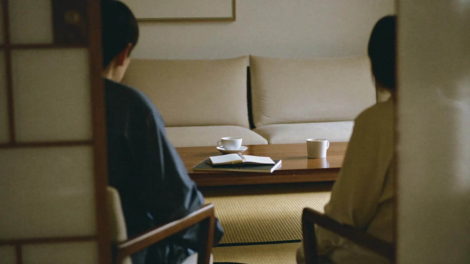 食卓で静かに話し合う夫婦の後ろ姿
