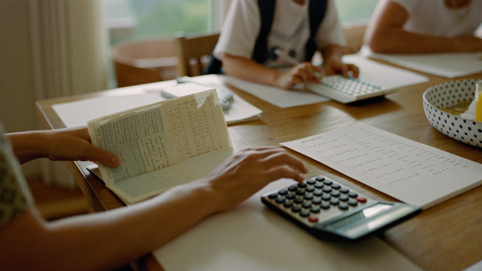 通帳と電卓で進学費用を計画する手元